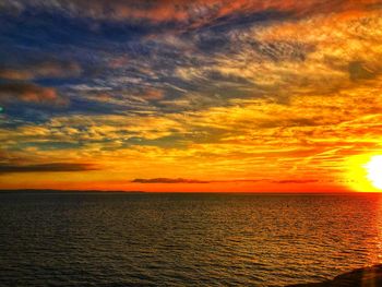 Scenic view of sea against dramatic sky during sunset