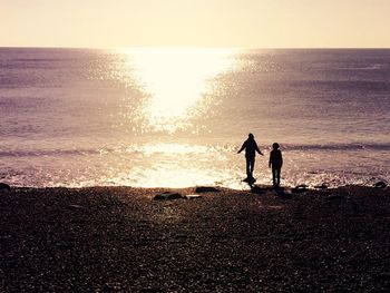 Silhouette of people on beach at sunset