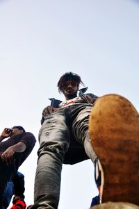 Low angle view of man photographing against sky