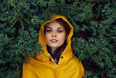 Portrait of young woman standing against plants