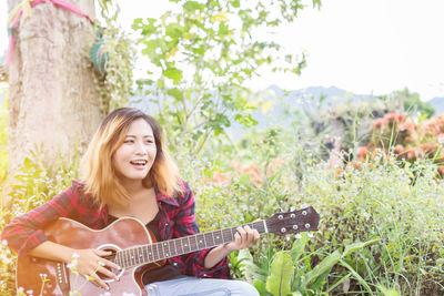 Portrait of smiling young woman playing guitar