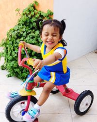 Full length of happy girl riding tricycle