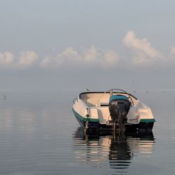Fishing boat moored on sea against sky