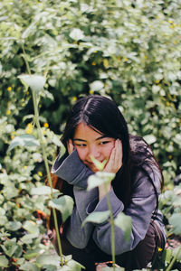 Portrait of young woman standing against plants