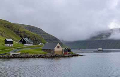 House by lake against sky