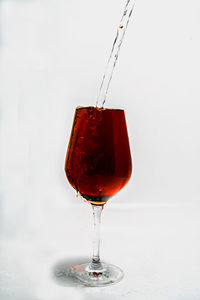 Close-up of red wine in glass against white background