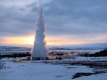 Scenic view of strokkur on snow covered landscape during sunset