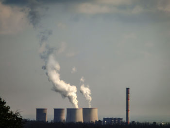 Smoke emitting from factory against sky