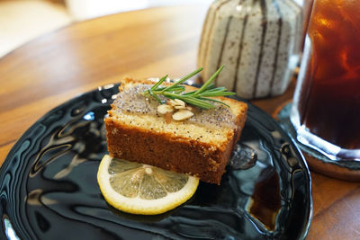 Close up lemon and poppy seed cake served with iced black coffee