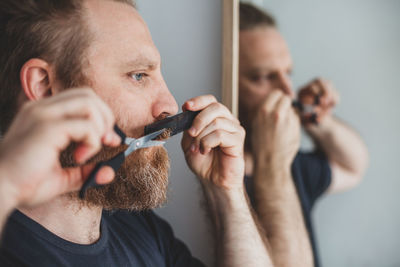 Man trimming beard with scissors at home