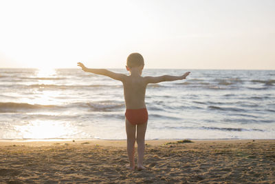 Rear view of boy standing at beach