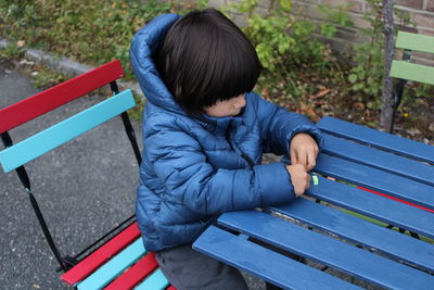 High angle view of boy sitting on bench