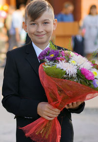 Portrait of smiling boy holding bouquet