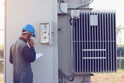 Male engineer talking on mobile phone while checking meter