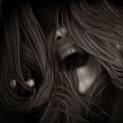 Close-up of young woman screaming in darkroom