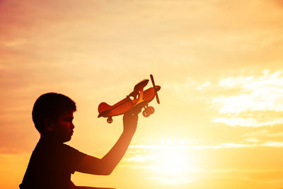 Full length portrait of silhouette boy against sky during sunset