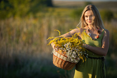 Portrait of young woman standing against plants