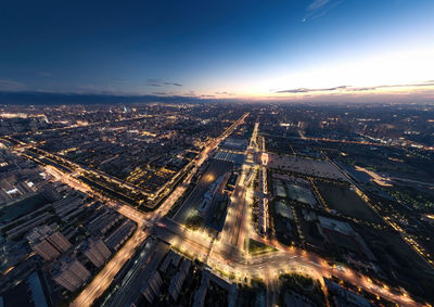 Aerial view of illuminated cityscape against sky at sunset