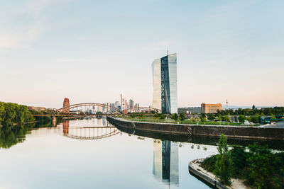 Bridge over river by buildings against sky