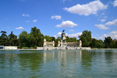 Monument by lake against blue sky
