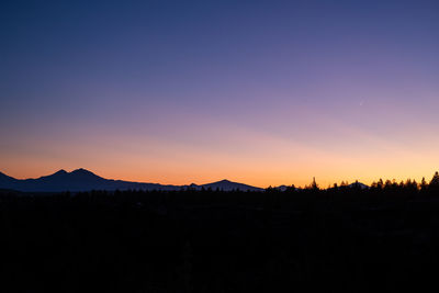 Scenic view of silhouette mountains against orange sky
