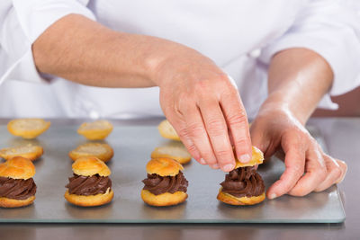 Midsection of chef preparing profiteroles in commercial kitchen