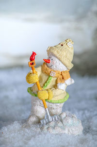 Comical snowman with a snow shovel, engages with a tiny red cardinal who lands on the shovel handle