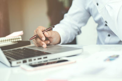 Midsection of man using mobile phone on table