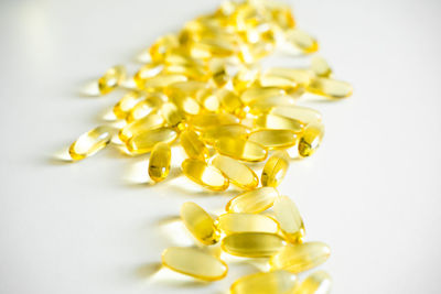 Close-up of pills spilling from bottle against white background