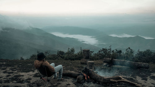 A man is sitting on the peak by the bonfire