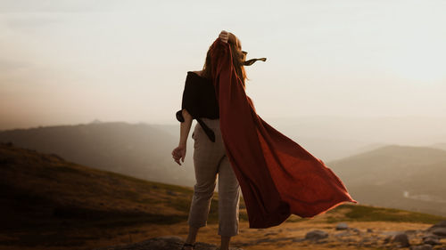 Woman standing on mountain road against sky