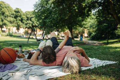 Grandfather and grandson lying down on picnic blanket at park