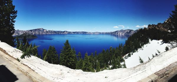 Scenic view of lake by snowcapped mountains against blue sky