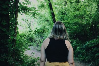 Rear view of woman standing in forest