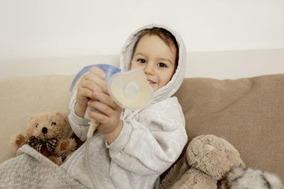 Sick little boy with inhaler for cough treatment. unwell kid doing inhalation on his bed. flu season