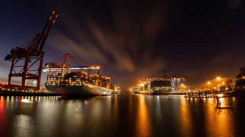 Container terminal with container ships, cranes and containers at night with beautiful clouds