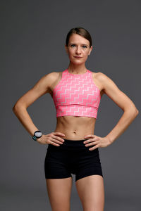 Portrait of young woman exercising against black background