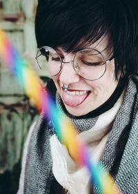 Multi colored light over woman wearing eyeglasses while sticking out tongue