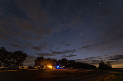 Road amidst trees against sky at night