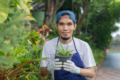 Portrait of smiling young man standing against plants