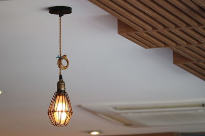 Low angle view of illuminated pendant light hanging from ceiling