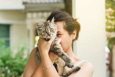 Portrait of woman carrying cat at home