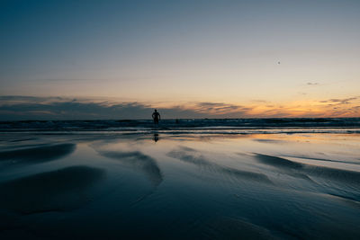 Silhouette person on beach against sky during sunset