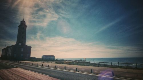 Road by sea against sky during sunset