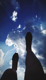 Low section of silhouette person against blue sky