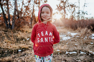 Portrait of young girl wearing a santa shirt in field with snow