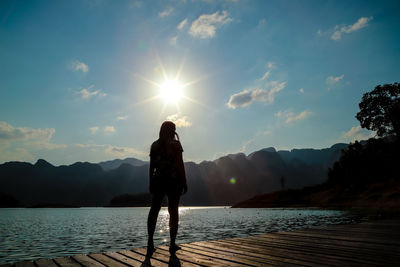 Rear view of silhouette man standing on mountain against sky