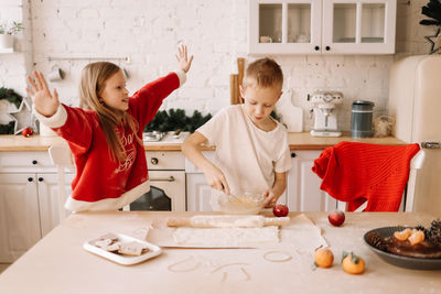 Two teenage children are having fun playing and preparing christmas food for  holiday in the kitchen