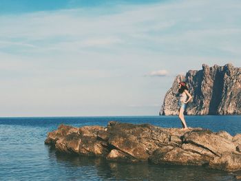 Young woman by sea against sky