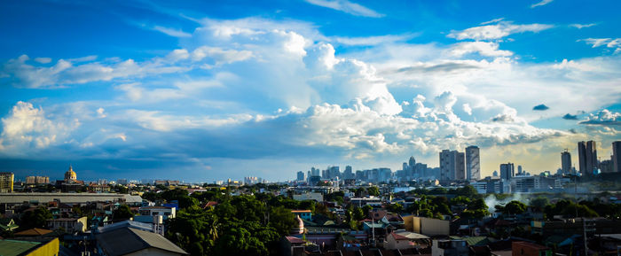 High angle view of city buildings against cloudy sky